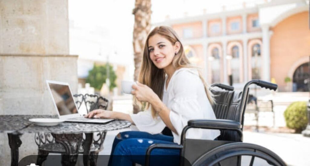 Happy disabled woman in wheelchair using laptop