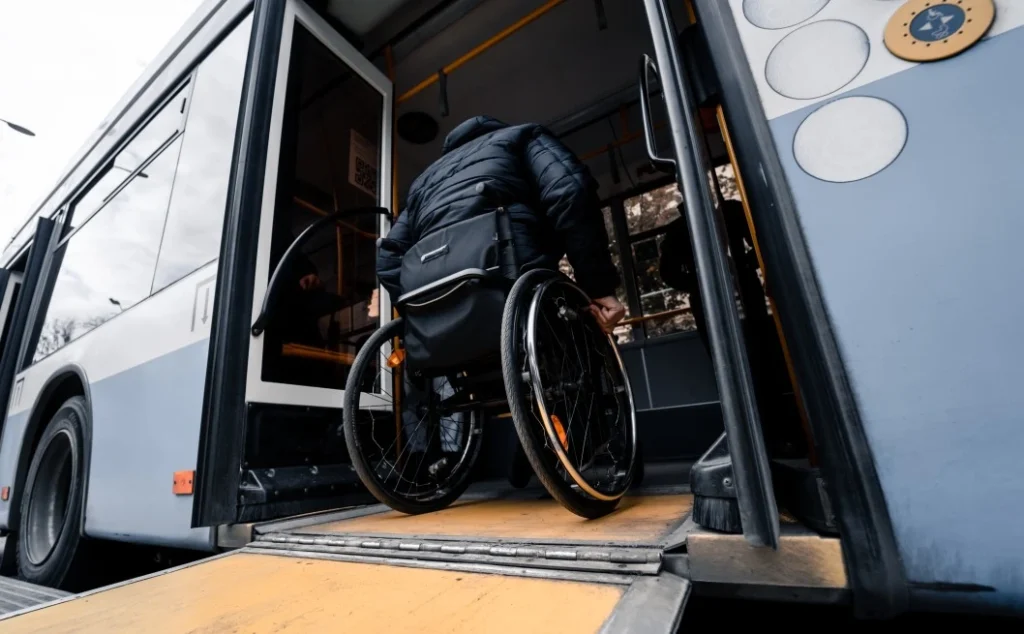 Disabled man in wheelchair getting on bus via ramp