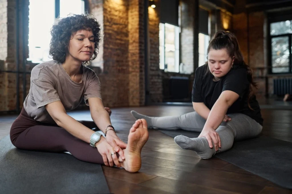 Disabled girl with down syndrome in yoga class with support worker